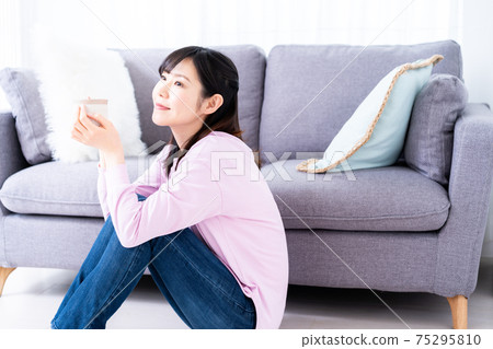 A woman relaxing with a cup of coffee in the living room 75295810