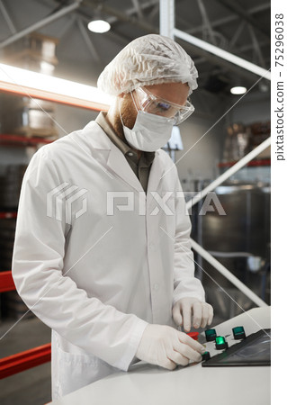 Man Pressing Buttons on Control Panel at Factory 75296038