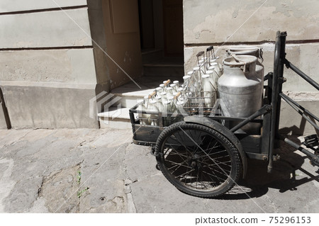 Bottles and aluminum cans of milk for delivery in vintage milkman bicycle 75296153