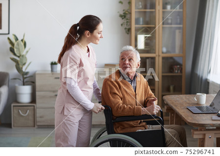 Young Woman Assisting Senior Man in Wheelchair 75296741