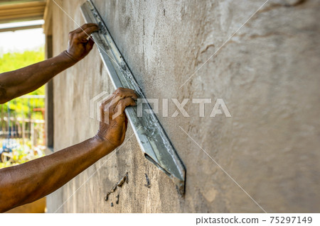 Home improvement and improvement concept. Close-up of workers plastering walls to build houses. Home improvement and improvement concept. Close-up of workers plastering walls to build houses. 75297149