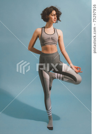 Girl raising both arms while standing on one leg and keeping her back straight 75297916