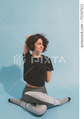 Teenage girl in sport clothing training yoga at the studio with blue background Teenage girl in sport clothing training yoga at the studio with blue background 75297931