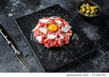 Tartar beef with a quail egg, capers and Parmesan cheese. Black background. Top view 75298745