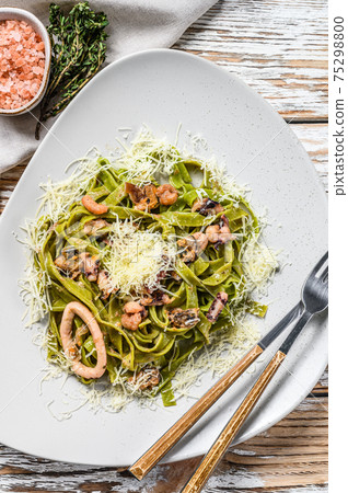 Green Fettuccine spinach pasta with seafood in cream sauce. White background. Top view 75298800
