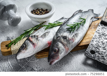 Raw seabass fish on a cutting board with spices, herbs. White background. Top view Raw seabass fish on a cutting board with spices, herbs. White background. Top view 75298851