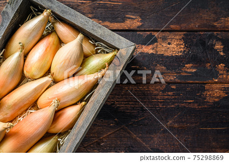 Raw Fresh Shallot onions Bulbs in a wooden market box. Dark Wooden background. Top view. Copy space 75298869
