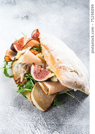 Ciabatta sandwich with arugula, fig, prosciutto and blue cheese. Gray background. Top view Ciabatta sandwich with arugula, fig, prosciutto and blue cheese. Gray background. Top view 75298899