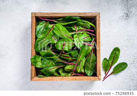 Raw Fresh green chard mangold leaves in a wooden box. White background. Top view 75298935