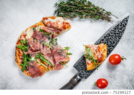 Italian Pizza with parma ham, arugula and cheeseon a kitchen table. White background. Top view 75299127