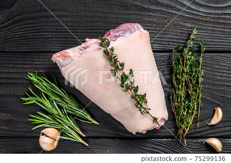 Raw Pork knuckle leg meat on kitchen table with herbs. Black wooden background. Top view Raw Pork knuckle leg meat on kitchen table with herbs. Black wooden background. Top view 75299136