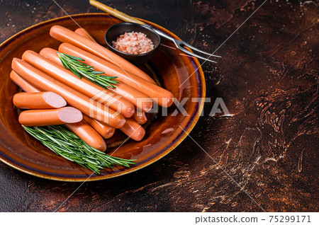 Wiener raw sausages in a rustic plate with herbs. Dark background. Top view. Copy space 75299171