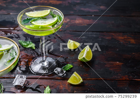 Mojito cocktail drink with lime, Ice and mint. Black wooden background. Top view. Copy space 75299239