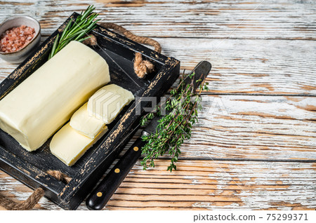 Butter Margarine block in a wooden tray with herbs. White wooden background. Top view. Copy space 75299371