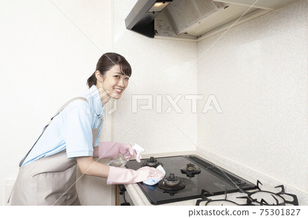 Female house cleaning worker cleaning the gas range Female house cleaning worker cleaning the gas range 75301827
