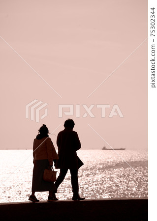 A couple walking on a seaside embankment 75302344