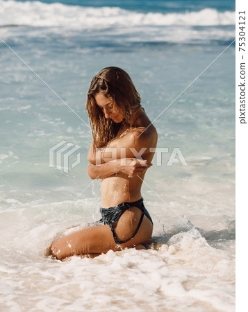 Attractive woman in black swimwear, caucasian model posing at ocean beach 75304121