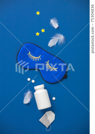 Blue sleeping mask, pills and herbal tea on blue background, concept of rest, quality of sleep, good night, insomnia, relaxation 75304836