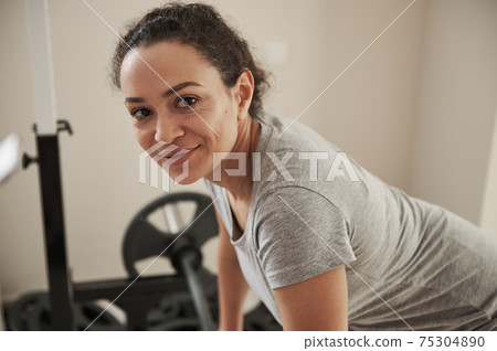 African young woman looking at camera during functional training in gym at home 75304890