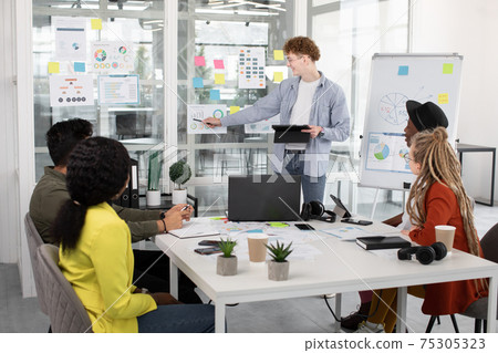 Young multiracial people having brainstorm meeting. Concept of business, coworking, strategy and technology. Young multiracial people having brainstorm meeting. Concept of business, coworking, strategy and technology. 75305323