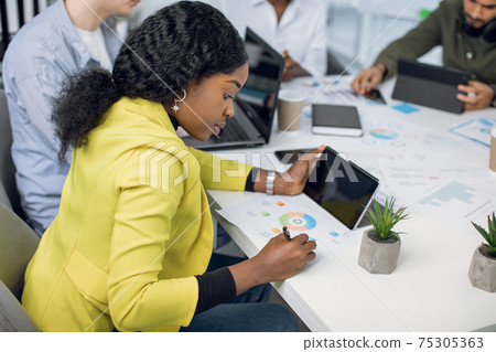 African woman and her coworkers working at office with gadgets 75305363