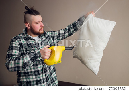 Dry cleaning worker removing dirt from sofa cushion indoors. 75305882