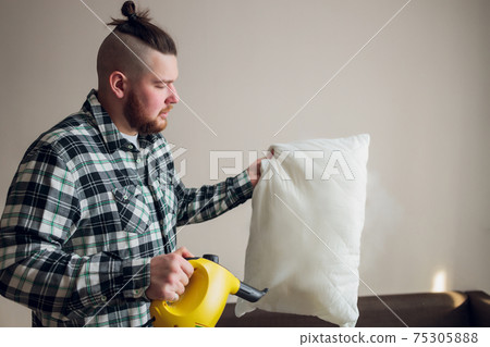 Dry cleaning worker removing dirt from sofa cushion indoors. Dry cleaning worker removing dirt from sofa cushion indoors. 75305888