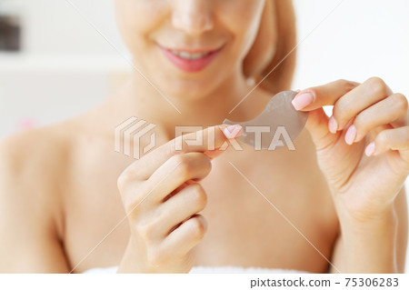 Young woman with beautiful skin puts black patches on her face 75306283