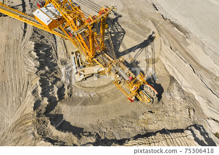 Top view of a bucket wheel excavator mining coal in an open pit mine. Top view of a bucket wheel excavator mining coal in an open pit mine. 75306418