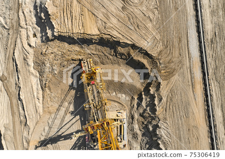 Aerial view of large heavy equipment machine mining natural resource. Coal mining by bucket wheel excavator. Heavy industry Aerial view of large heavy equipment machine mining natural resource. Coal mining by bucket wheel excavator. Heavy industry 75306419