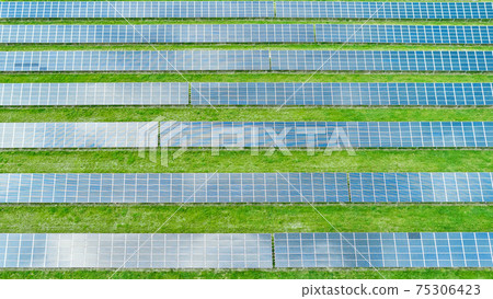 Equal lines of solar panels in the green field. Top view of solar power station for generation green energy Equal lines of solar panels in the green field. Top view of solar power station for generation green energy 75306423