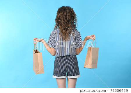Child with a packet isolated on blue background. Holiday present, shopping. Kid happy shopping in mall. Child with a packet isolated on blue background. Holiday present, shopping. Kid happy shopping in mall. 75306429