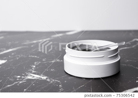 A white jar with eye patches and spatula on the marble table with copy space. A white jar with eye patches and spatula on the marble table with copy space. 75306542