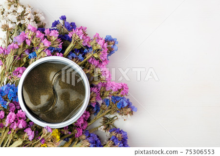 Top view on the can with gold collagen hydrogel eye patches with colorful flowers on the white background with copy space. Top view on the can with gold collagen hydrogel eye patches with colorful flowers on the white background with copy space. 75306553
