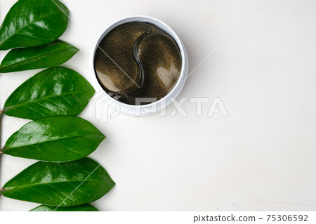 Hydrogel eye patches and green branch with leaves on a white background with copy space. Hydrogel eye patches and green branch with leaves on a white background with copy space. 75306592