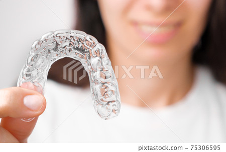 Close up orthodontic transparent aligner in womans hand. Removable braces. Close up orthodontic transparent aligner in womans hand. Removable braces. 75306595