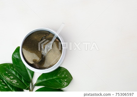 Hydrogel eye patches and green branch with leaves on a white background with copy space. Hydrogel eye patches and green branch with leaves on a white background with copy space. 75306597