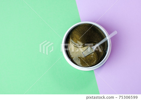 Can with gold collagen hydrogel eye patches with spatula on the green purple background. Cosmetic for skin care. Product for face and anti aging wrinkles Can with gold collagen hydrogel eye patches with spatula on the green purple background. Cosmetic for skin care. Product for face and anti aging wrinkles 75306599