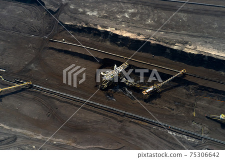 Top view of a mining quarry with huge equipment for coal or natural raw material mining. Working bucket wheel excavator. Top view of a mining quarry with huge equipment for coal or natural raw material mining. Working bucket wheel excavator. 75306642