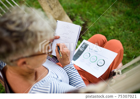Top view of active senior woman working outdoors in garden, home office concept. 75307021