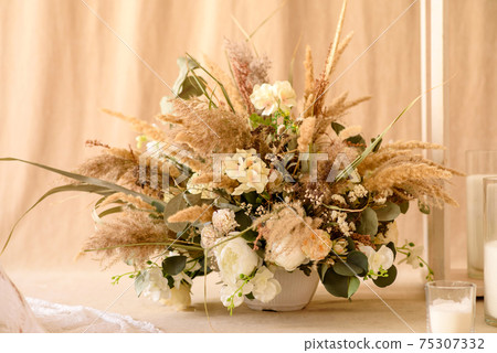Decorations from dry beautiful flowers in a white vase on a beige fabric background Decorations from dry beautiful flowers in a white vase on a beige fabric background 75307332