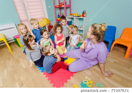 Lovely preschoolers listening young teacher very carefully Lovely preschoolers listening young teacher very carefully 75307631