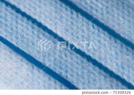 Bright blue face mask close up gives abstract dimple texture. Bright blue face mask close up gives abstract dimple texture. 75309326