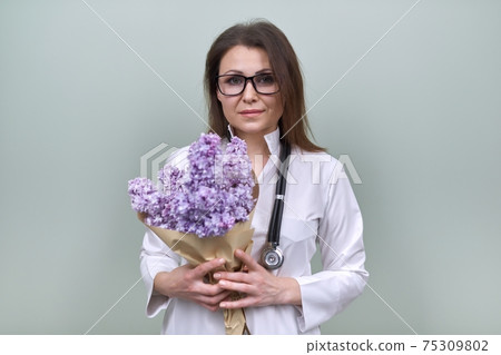 Portrait of female doctor with stethoscope with bouquet of lilac flowers Portrait of female doctor with stethoscope with bouquet of lilac flowers 75309802