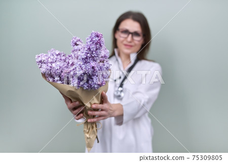 Bouquet of lilac flowers in the hands of woman doctor Bouquet of lilac flowers in the hands of woman doctor 75309805