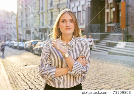 Urban portrait of beautiful young blonde woman on city street at sunset Urban portrait of beautiful young blonde woman on city street at sunset 75309808