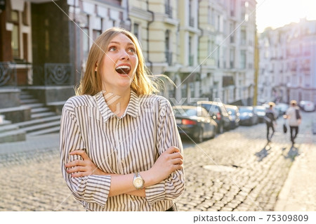 Beautiful emotional young woman on a city street Beautiful emotional young woman on a city street 75309809