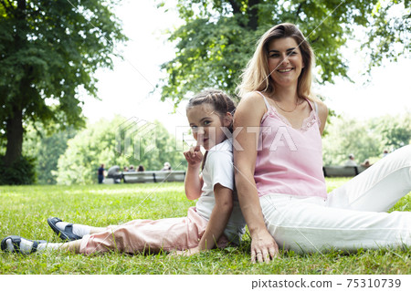 young pretty mother walking with little cute daughter outside in green park, lifestyle poeple concept young pretty mother walking with little cute daughter outside in green park, lifestyle poeple concept 75310739