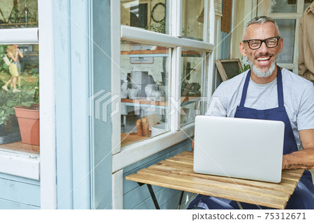 Happy middle aged caucasian man working on computer Happy middle aged caucasian man working on computer 75312671