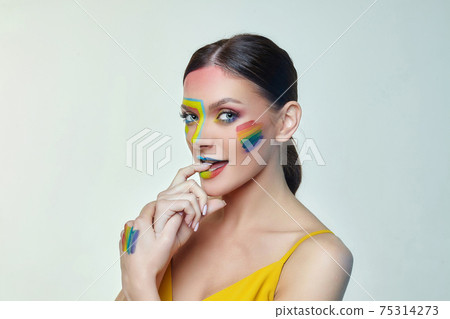 portrait of an attractive girl with bright makeup. A rainbow LGBT flag is depicted on her cheek portrait of an attractive girl with bright makeup. A rainbow LGBT flag is depicted on her cheek 75314273